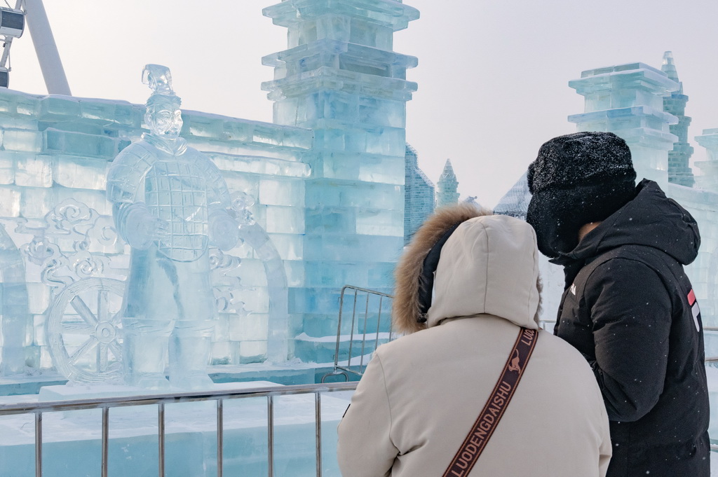 1月23日，在哈爾濱冰雪大世界園區(qū)，游客在“冰馬俑”冰雕前游玩。