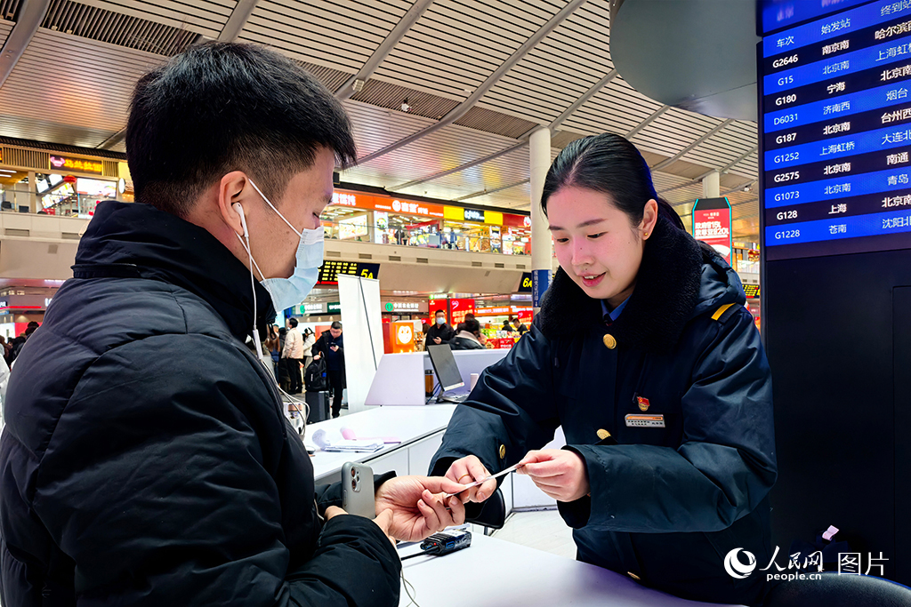 1月13日，濟(jì)南西站客服中心的客運(yùn)員根據(jù)旅客的換乘需求，在提示卡上標(biāo)記路線，幫助旅客便捷換乘。人民網(wǎng)記者 劉祺攝