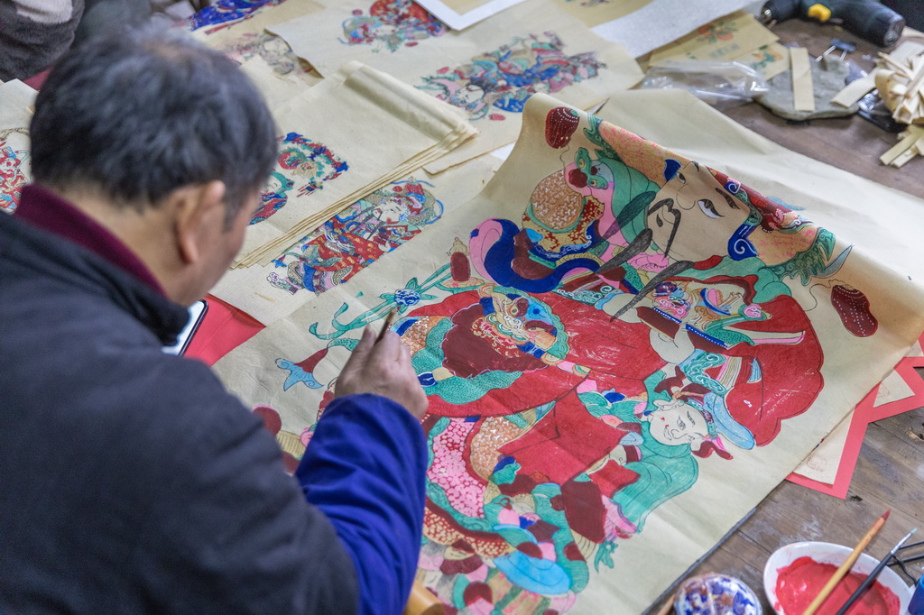 1月14日，在重慶市梁平區(qū)屏錦鎮(zhèn)，梁平木版年畫國(guó)家級(jí)代表性傳承人徐家輝在工作室內(nèi)為年畫描色。