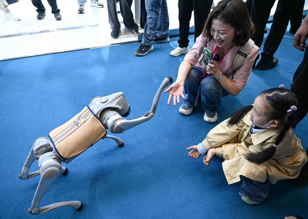 4月14日，觀眾在第五屆消博會宇樹科技展臺與機器狗握手。新華社記者 蒲曉旭 攝