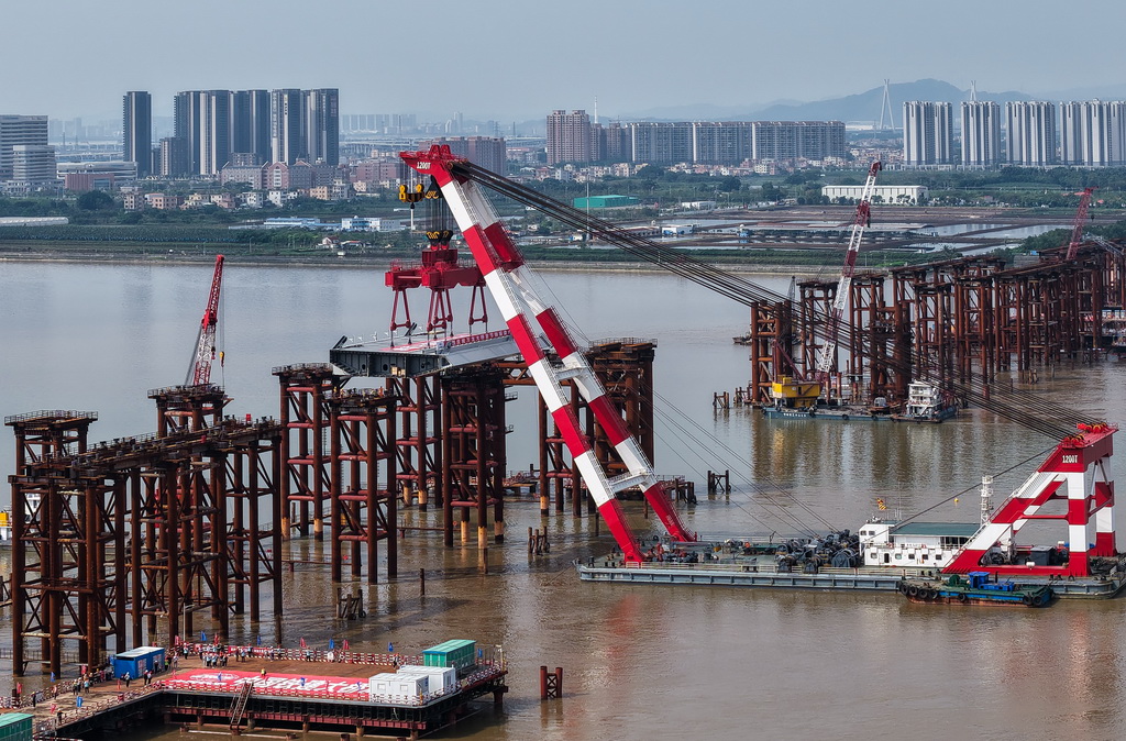 4月29日，1200噸大型浮吊將重達606噸的首節(jié)鋼箱梁吊裝架設到萬龍大橋鋼梁支架上（無人機照片）。