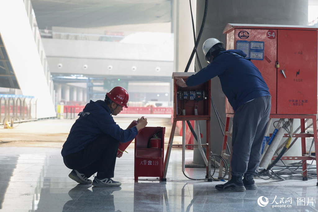 施工人員在現(xiàn)場檢查滅火器、配電箱等裝置，確保施工安全。