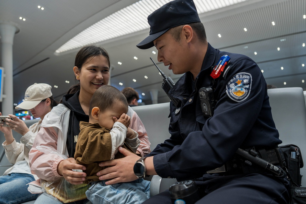 5月1日，烏魯木齊鐵路公安處烏魯木齊站派出所民警向帶小孩的旅客提示乘車安全。新華社發(fā)（葉帥 攝）