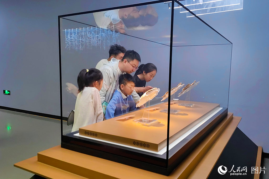 2025年5月3日，河南安陽殷墟博物館內(nèi)，游客駐足在甲骨文展區(qū)。3000年前的龜甲歷經(jīng)歲月打磨，仍清晰可見蒼勁的刻痕，游客透過這些承載著文明密碼的古老文字，仿佛能看到祭祀的盛大場景，真切觸摸到華夏文明傳承的脈絡(luò)，感受著中華文化穿越千年的強(qiáng)大生命力。人民網(wǎng)記者 單芳攝