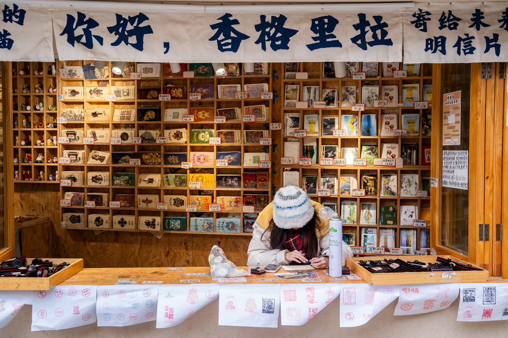 一名游客在云南省迪慶州香格里拉市獨(dú)克宗古城寫明信片（2025年3月7日攝）。