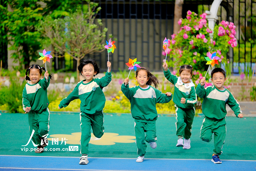 2025年5月8日，在江蘇省南通市，崇川區(qū)沁園幼兒園的小朋友手持小風(fēng)車(chē)在操場(chǎng)上微笑著奔跑。徐培欽攝（人民圖片網(wǎng)）