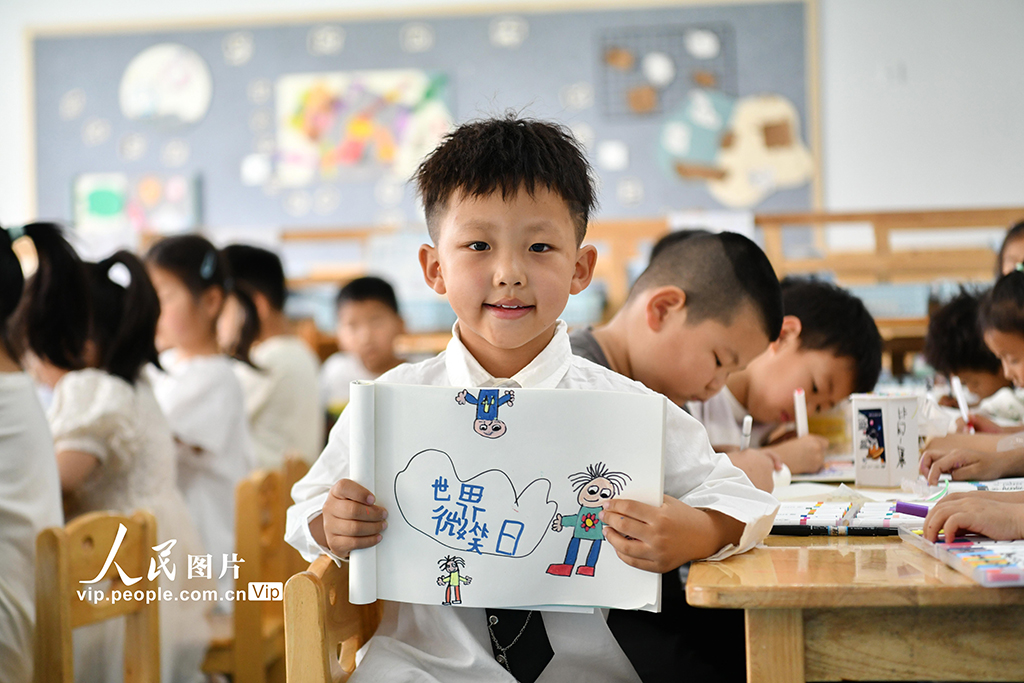 2025年5月7日，安徽省阜陽(yáng)市阜南縣駱寨社區(qū)幼兒園的孩子展示自己繪制心中的笑臉。呂乃明攝（人民圖片網(wǎng)）