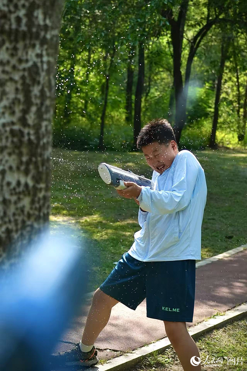 2025年5月29日，夏日炎炎，在遼寧省沈陽市沈河區(qū)體院公園的草地上，小朋友們正在進(jìn)行一場酣暢淋漓的水槍大戰(zhàn)。人民網(wǎng)記者 周頌雪攝