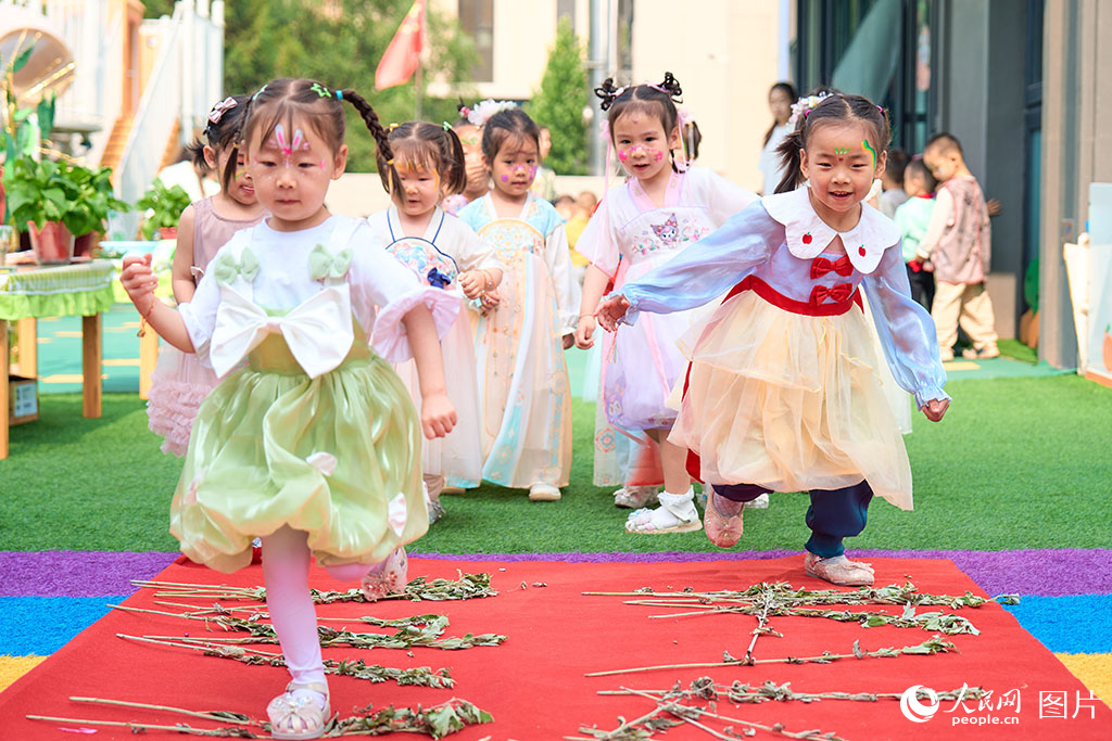 2025年5月30日，山西省太原市，孩子們用腳踩艾葉的方式喜迎端午六一雙節(jié)。人民網(wǎng) 張超寧攝
